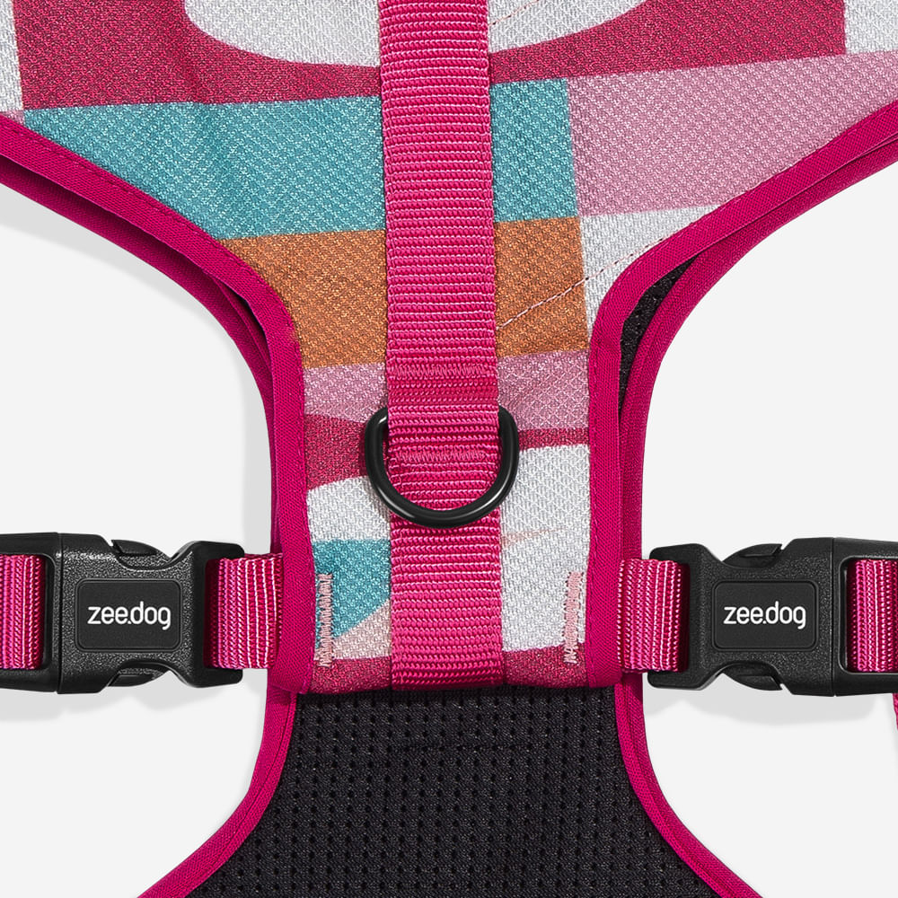 Colourful geometric-patterned dog harness with pink trim and black buckles.