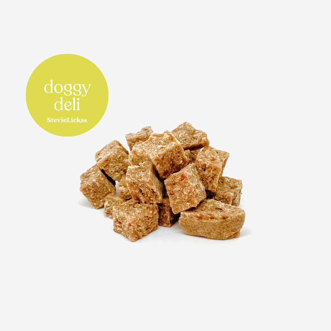 A pile of small, golden-brown beef and chicksen kibble bite dog treats on a white background, labeled "doggy deli" by StevieLicks.