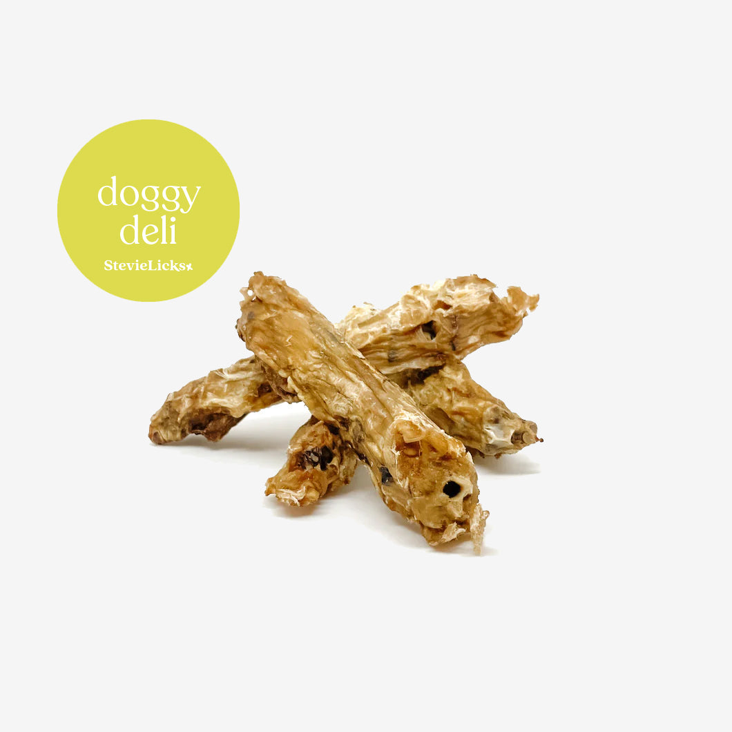 Three natural dog treats resembling dried chicken strips, accompanied by a green circular label reading "doggy deli StevieLicks."