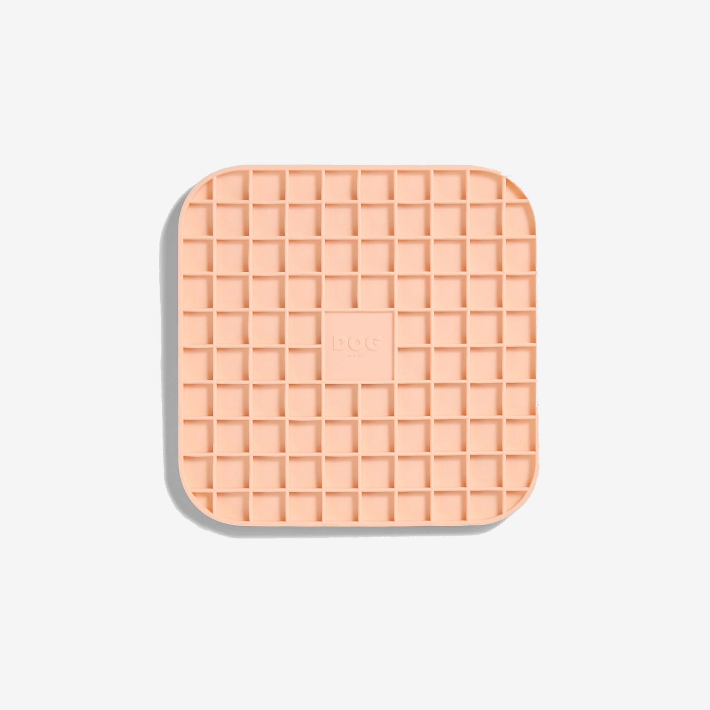 A blush coloured square lick mat with rounded edges and gridded squared inner pockets.