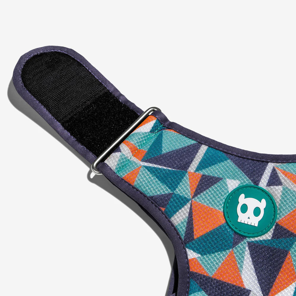 Colourful geometric patterned dog harness with a rubber skull logo and metal adjustable fastener.