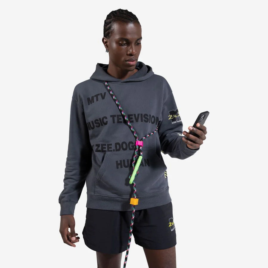A person wearing a grey hoodie with "MTV MUSIC TELEVISION" printed on it, holding a smartphone and a colourful dog leash.