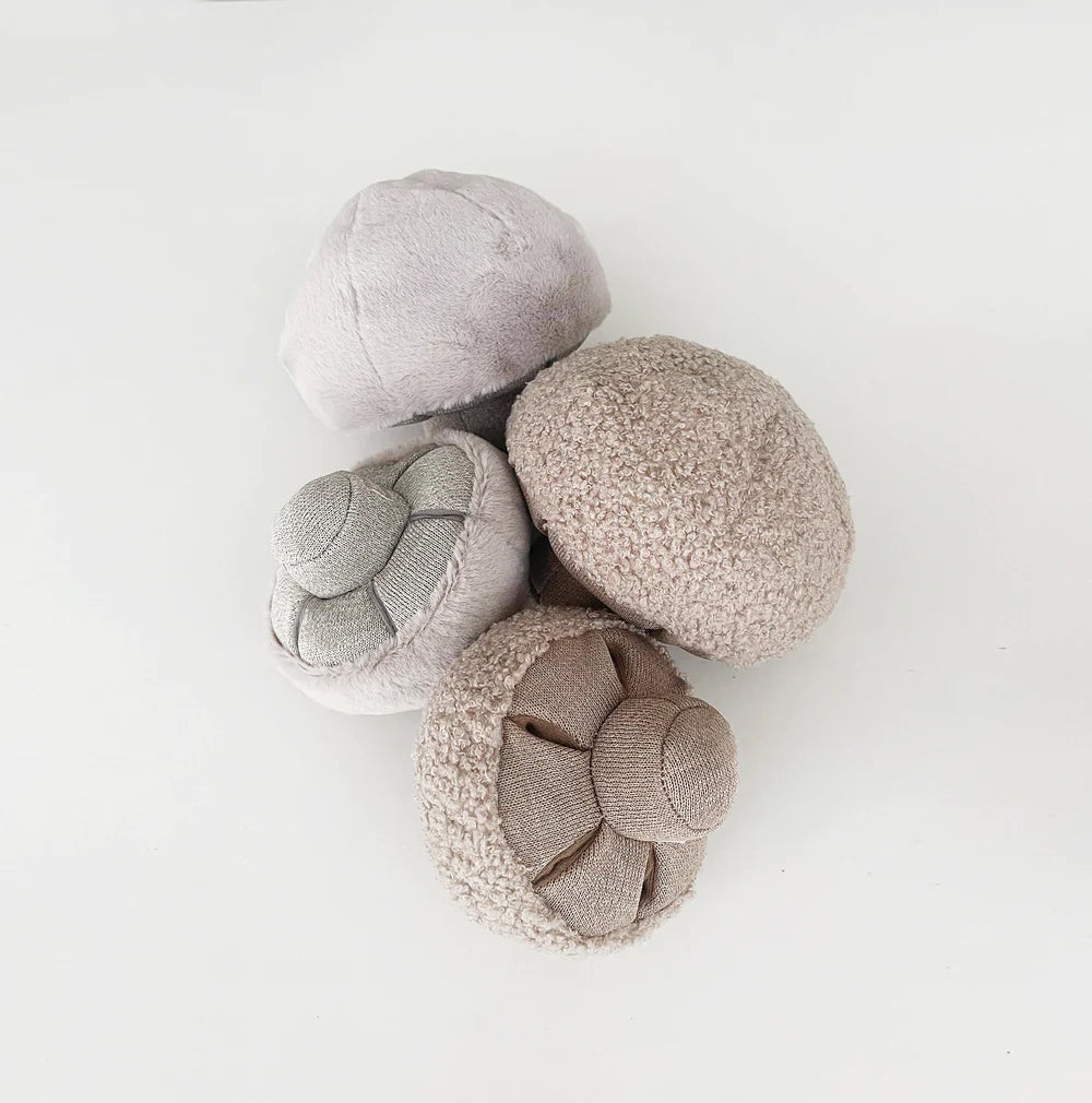 Four plush mushrooms in grey and brown tones on a white background.