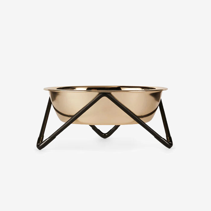 Modern stainless steel gold-coloured bowl on a black triangular black stand against a white background.