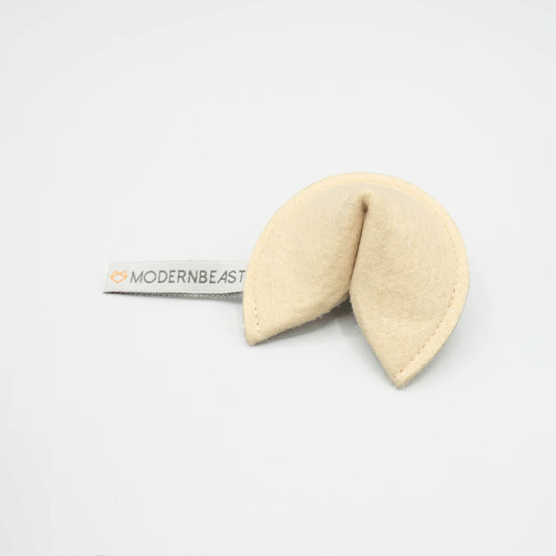 A plush fortune cookie with a tag saying "MODERN BEAST" on a white background.