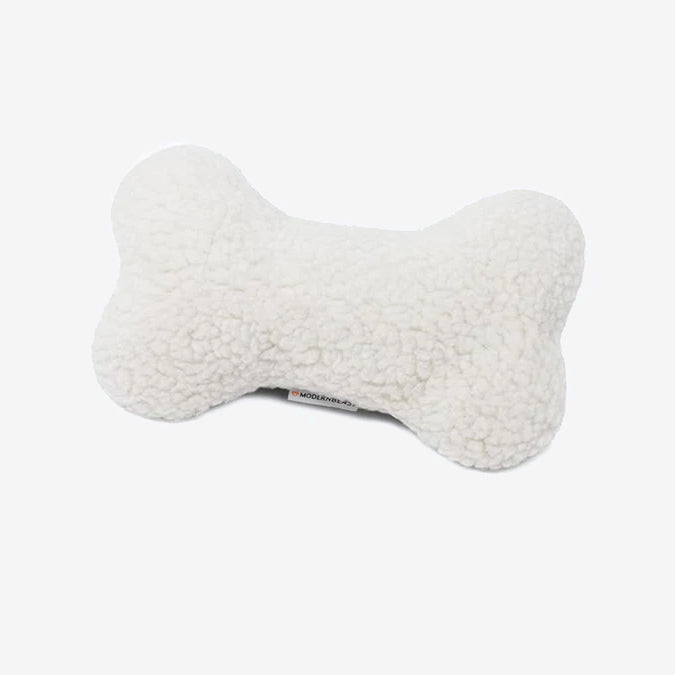 A plush white bone-shaped dog toy with a visible tag on a white background.