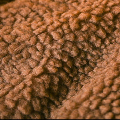 Close-up of a textured brown knitted fabric with a detailed stitch pattern.