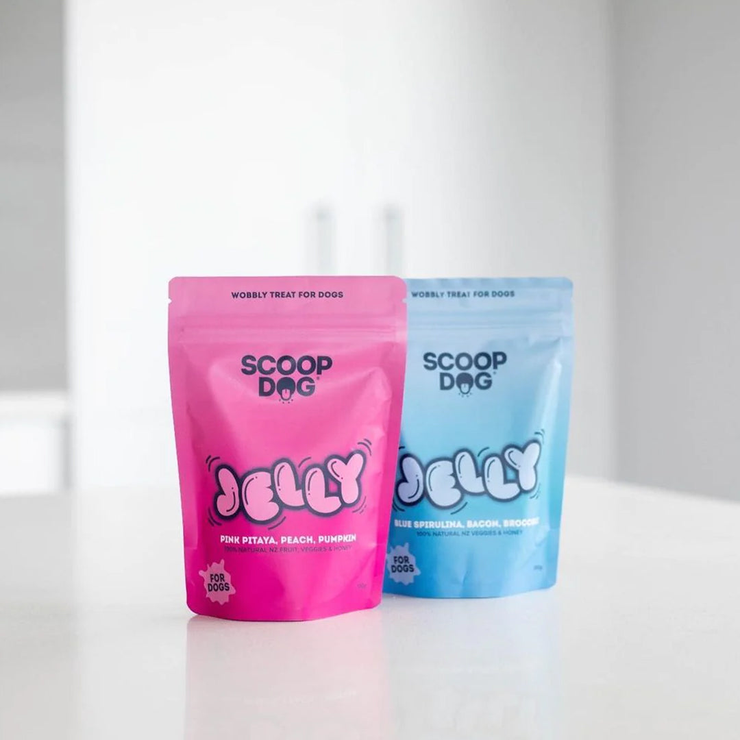 Two colorful dog treat packages, one pink and one blue, labeled "SCOOP DOG JELLY," on a white surface.