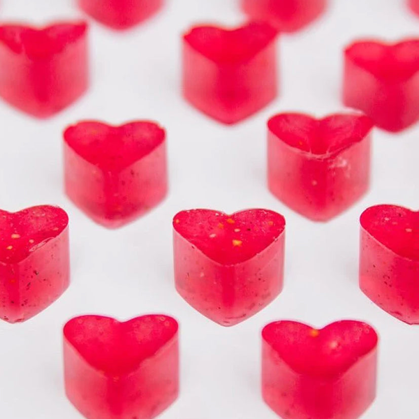 Red heart-shaped gummy dog candies arranged on a white background.