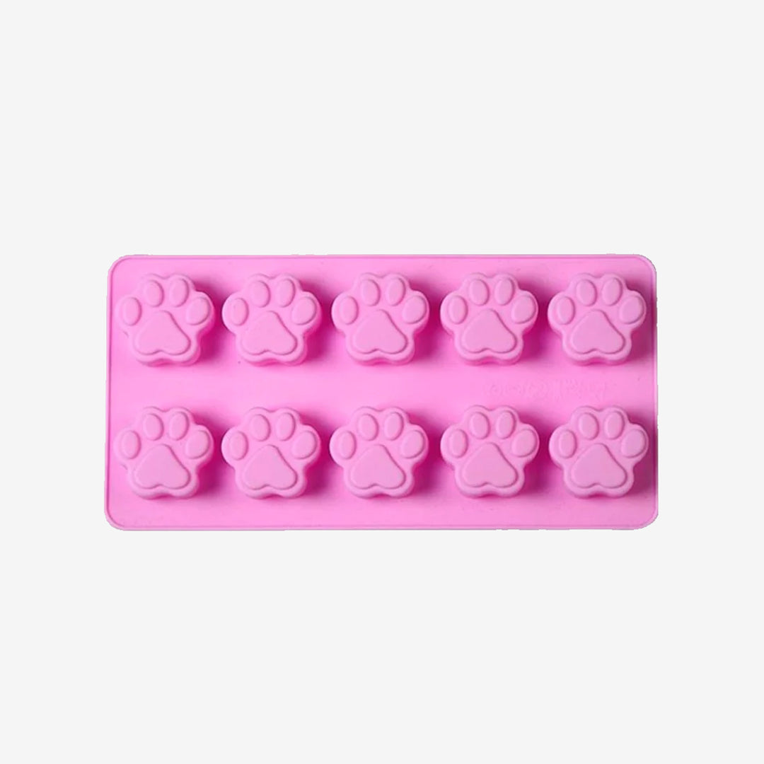 A pink silicone mold with multiple paw print cavities.