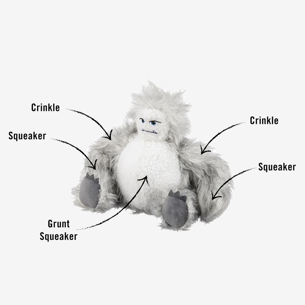A plush yeti toy with crinkle, squeaker, and grunt sounds, showcasing its playful features labeled on its soft, furry body.