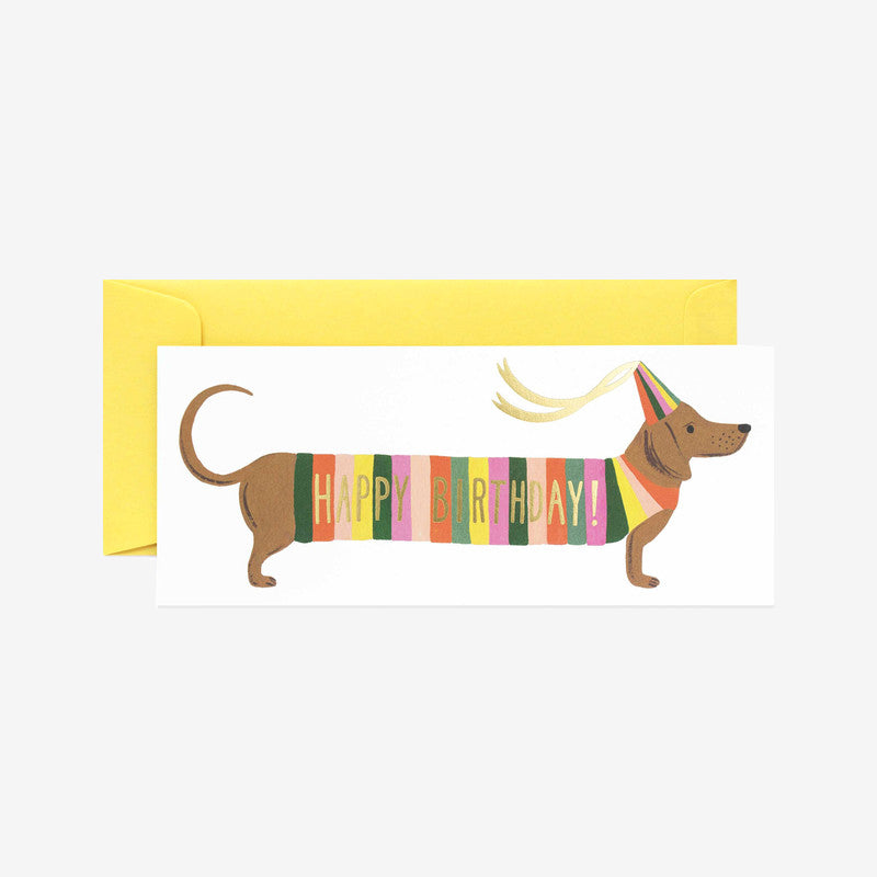 Colourful birthday card featuring a dachshund in a party hat, with "HAPPY BIRTHDAY!" written in vibrant stripes. Yellow envelope included.