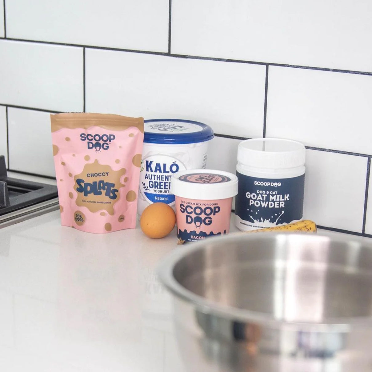 Dog food products on a kitchen counter with tiles in the background.