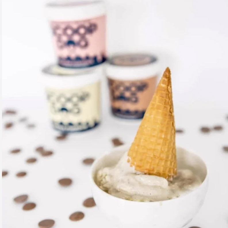 An overturned ice cream cone in a bowl with blurred ice cream containers in the background.