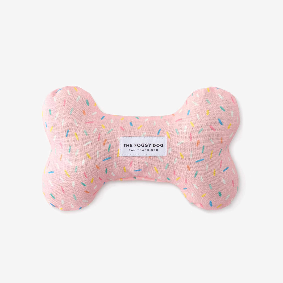 A pink dog bone-shaped pillow with colorful speckles and a label reading "THE FOGGY DOG".