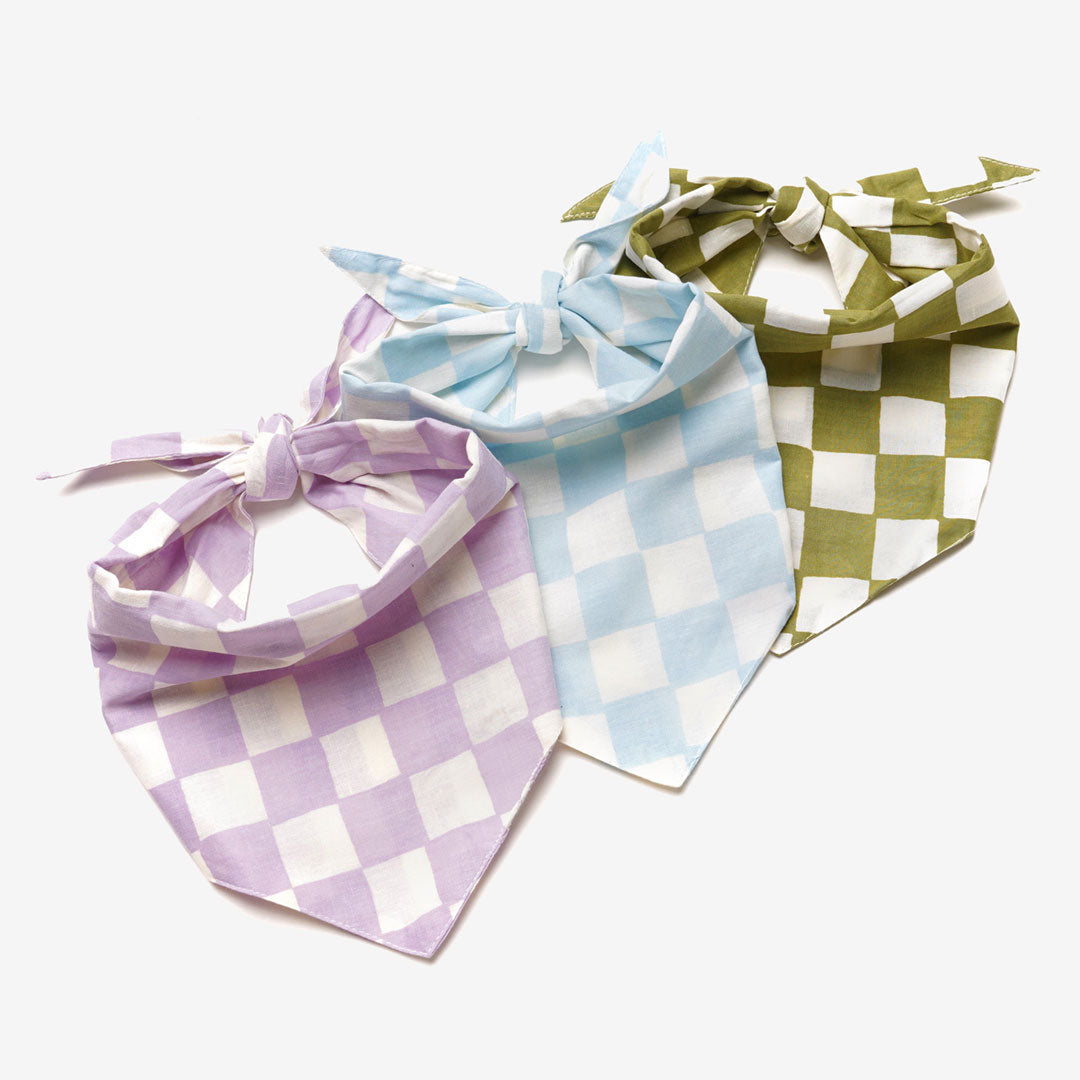 3 checkered dog bananas, lilac and white, pale blue and white, and khaki and white, neatly tied on a white background.