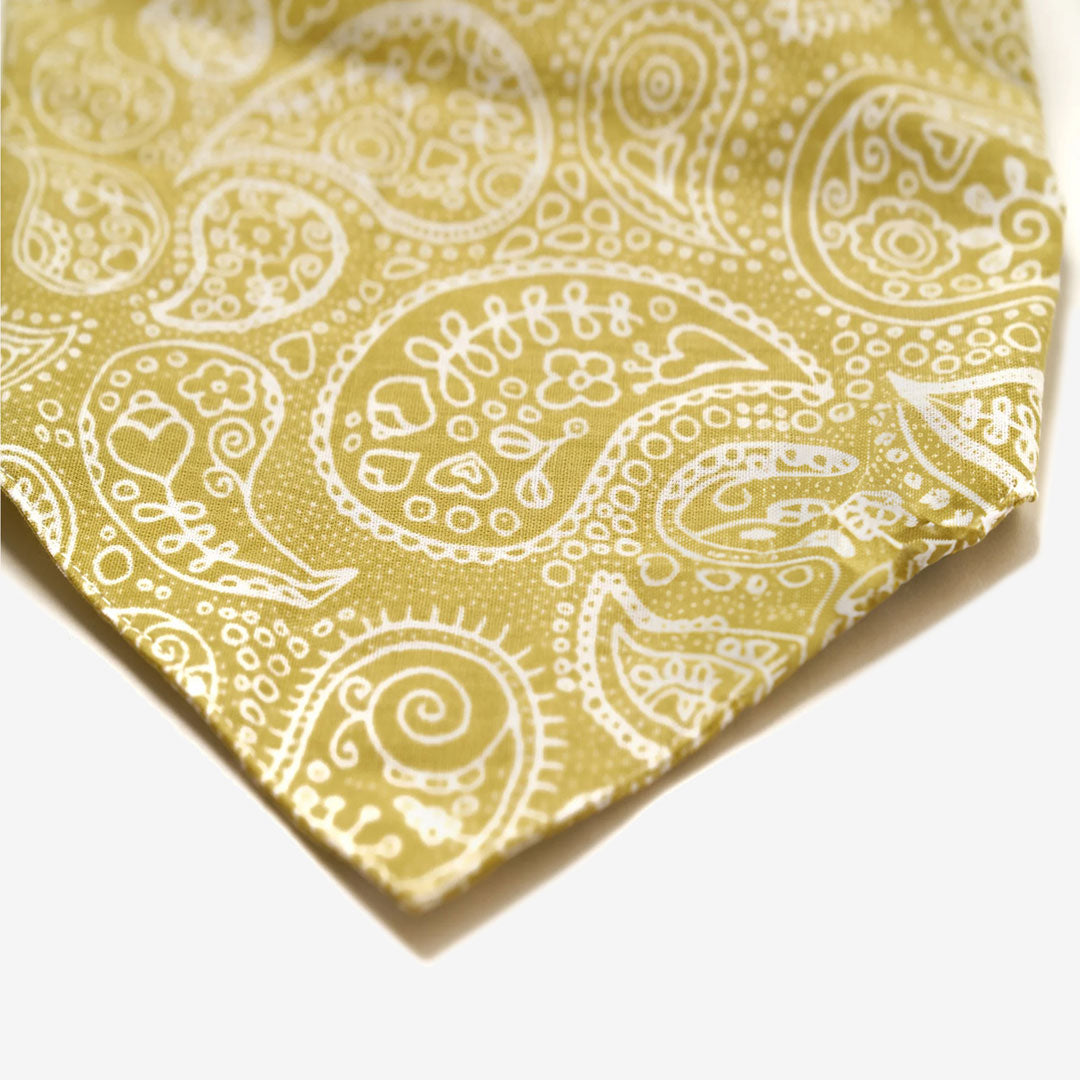 Close up fabric, triangular cut with a white paisely design on a mustard coloured base.