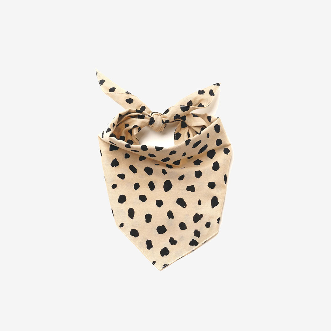 A beige dog bandana with a black irregular dotted pattern, resembling an animal print. Isolated on a white background.