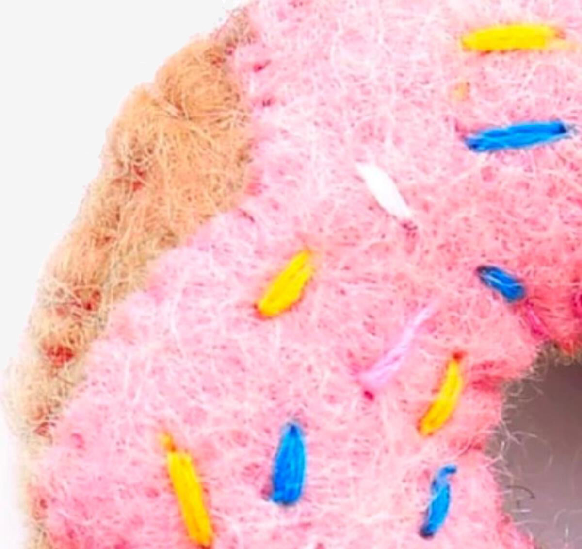 Close-up of a pink textile with colorful stitch details.