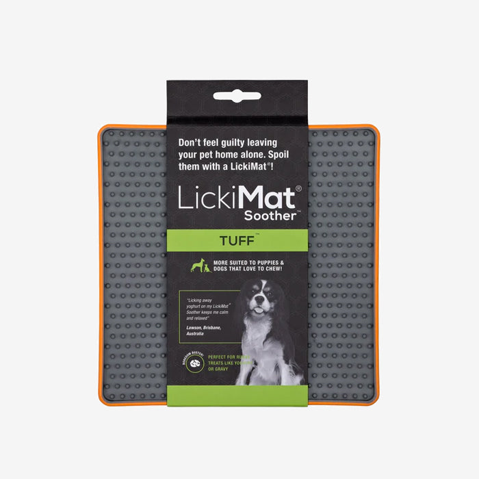 Grey LickiMat Soother TUFF with orange rim, a chew-resistant feeding mat for dogs, designed to calm pets while enjoying treats, with a playful dog image.