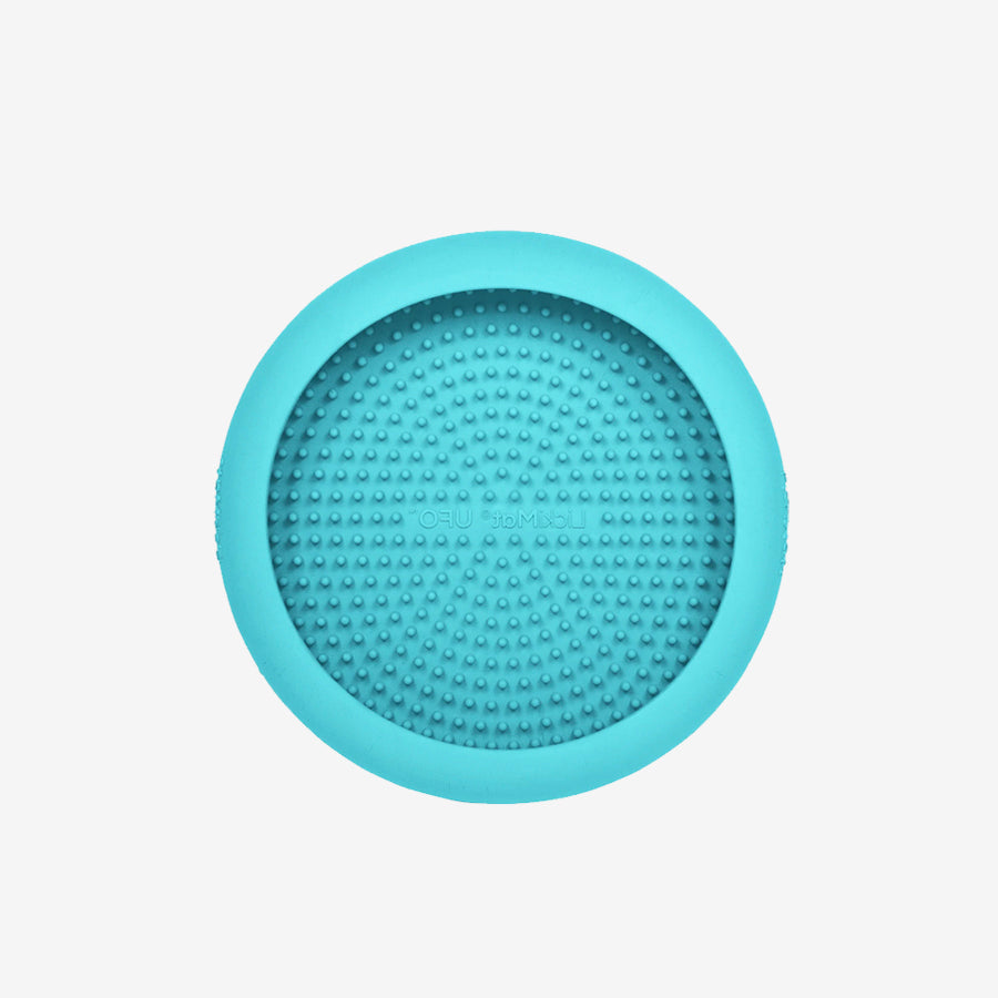 A round turquoise silicone mat featuring a textured surface with small raised dots, ideal for grip and stability.