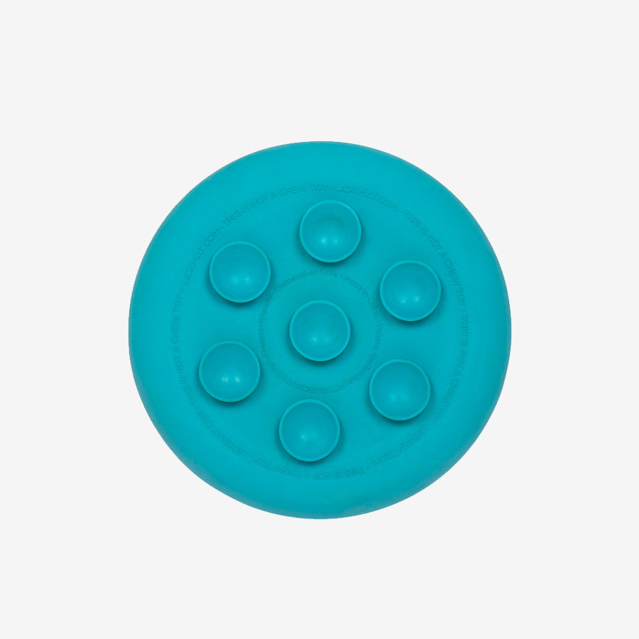 A blue silicone feeding mat with eight circular compartments for food or treats, labeled "This is not a chew toy."