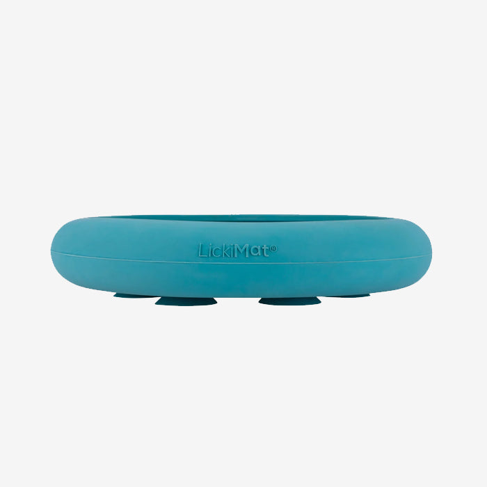 A teal LickiMat with a smooth surface designed for pet feeding, featuring a logo and suction feet for stability.