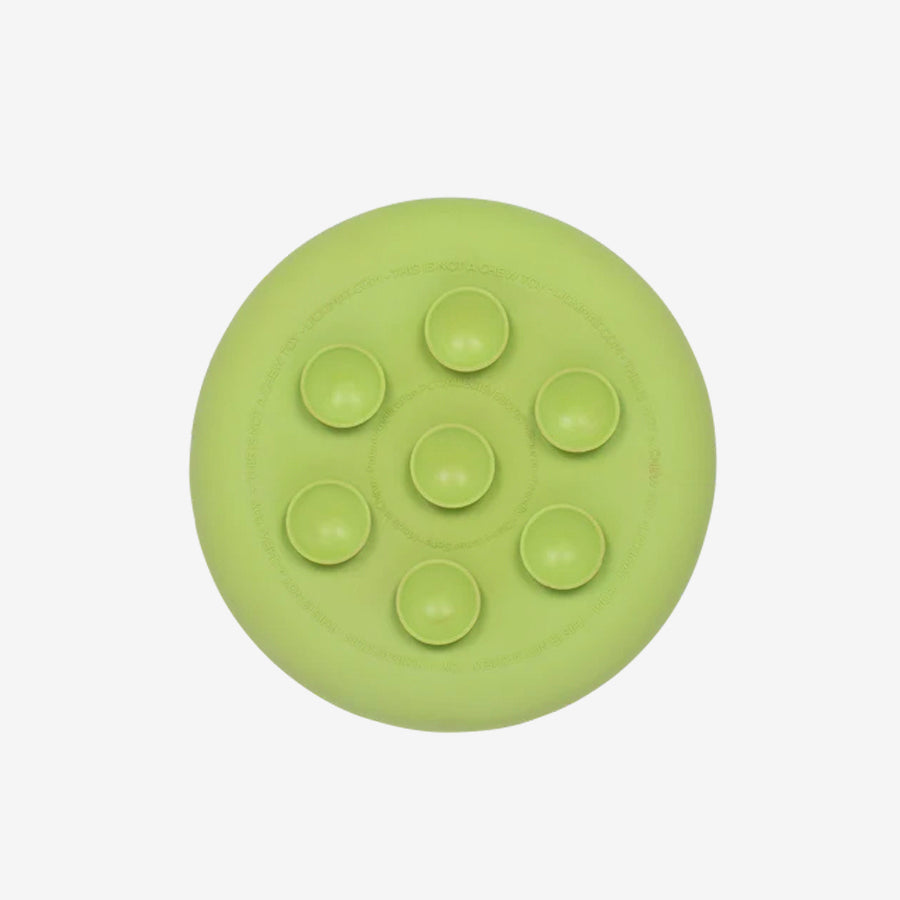Round, light green silicone mat with seven round raised bumps, designed for massage or sensory stimulation.