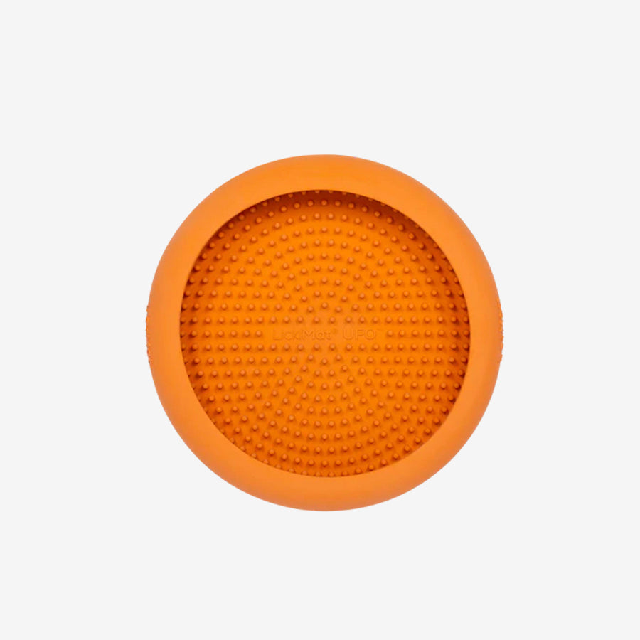 Round orange silicone dog licking mat with textured surface for promoting slow feeding and mental stimulation.