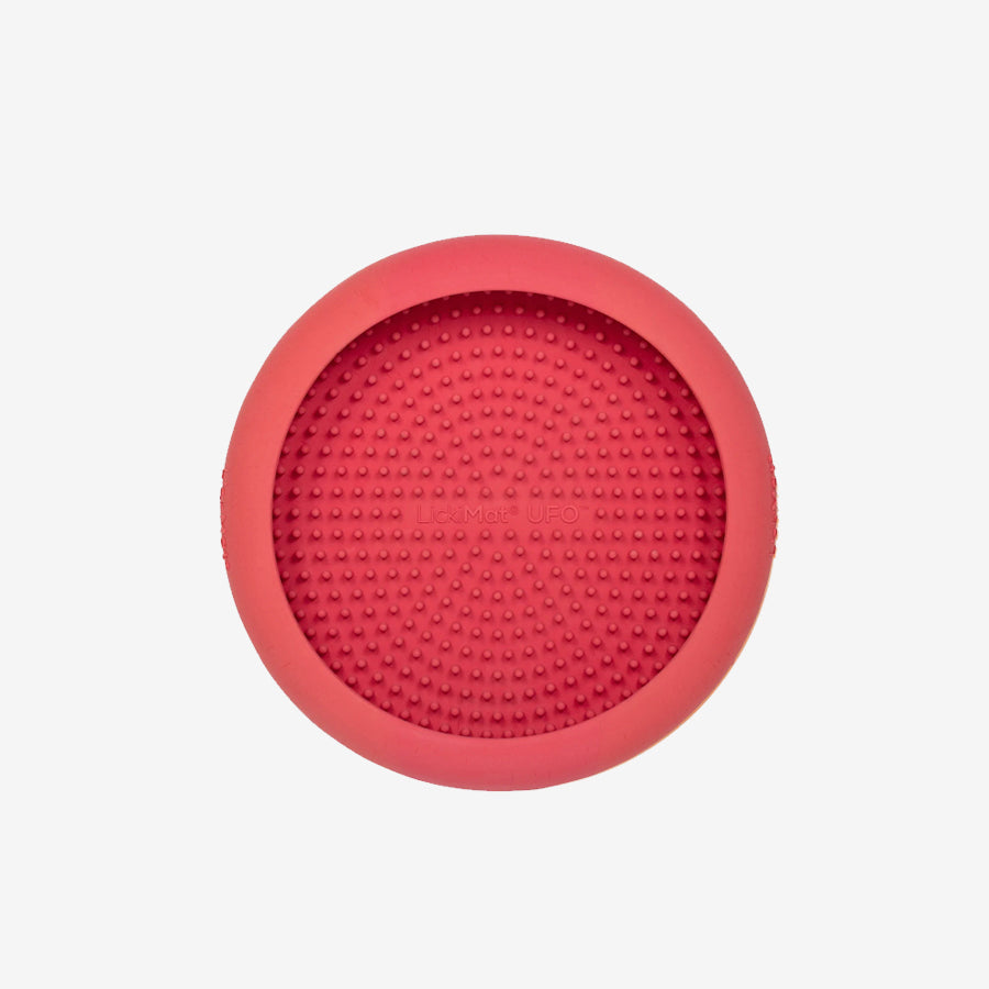 A round, pink silicone LickMat UFO, featuring a textured surface of small raised dots for pet enrichment and licking activities.