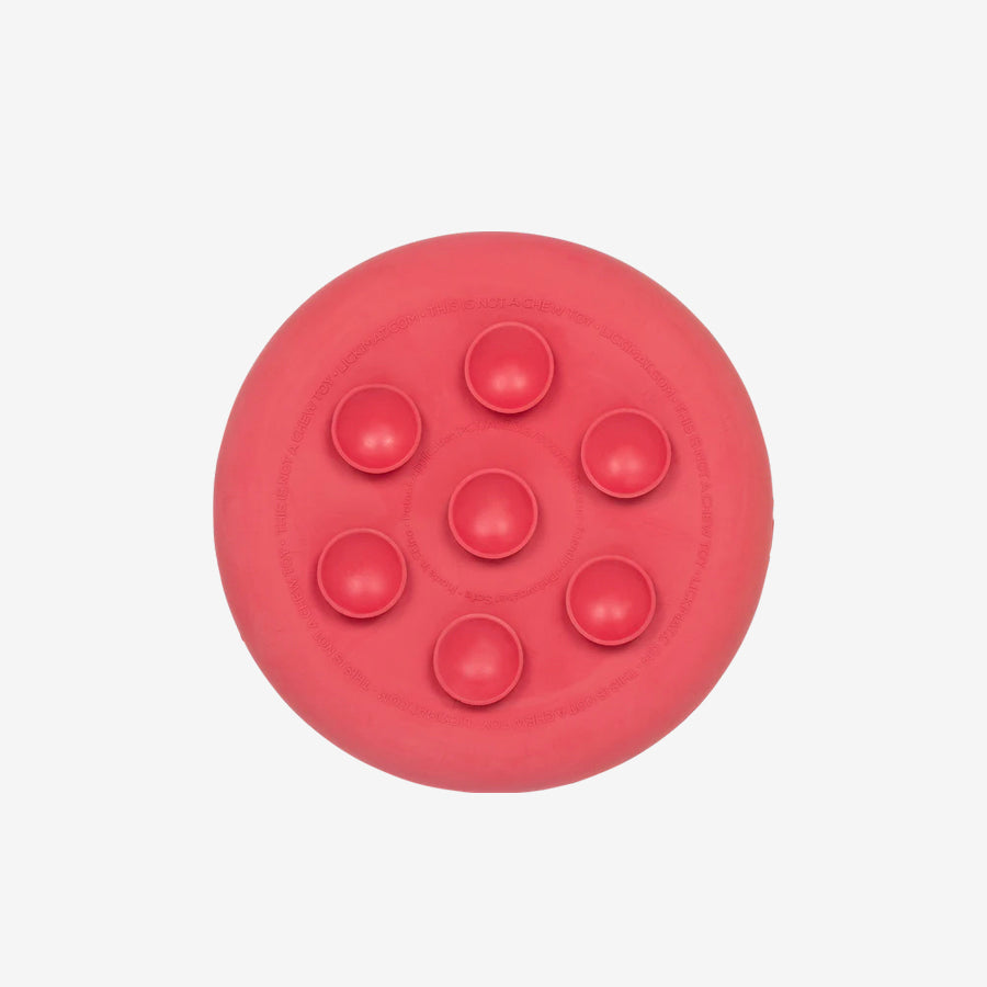 A close-up of a circular, vibrant red object, partially obscured, with smooth edges and a glossy surface against a white background.
