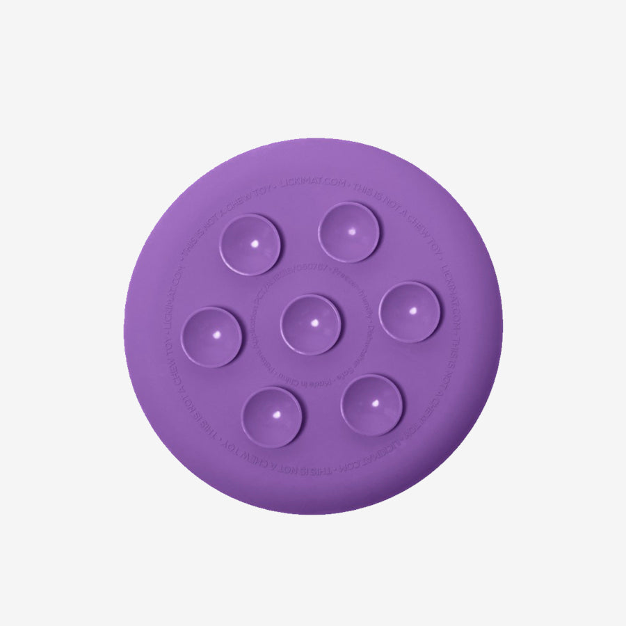 A round purple silicone mat with a textured surface and four small raised circles, designed for pet enrichment activities.