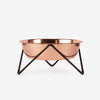 A stylish copper bowl with a sleek black metal stand, perfect for serving or decorative use.