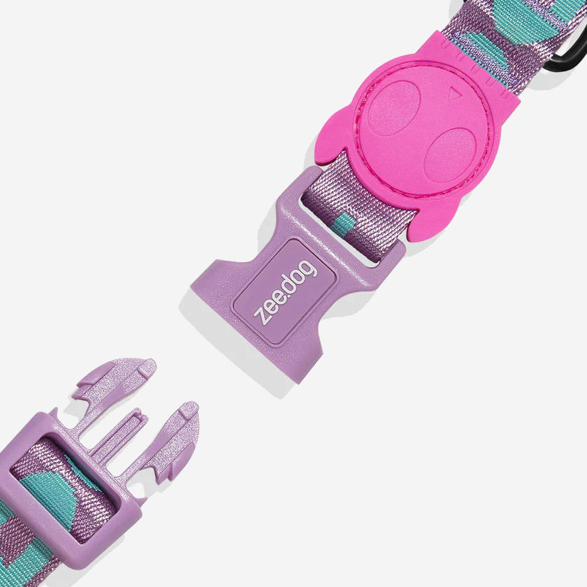 A Zee.Dog brand dog collar buckle in pink and purple with a partially visible strap.