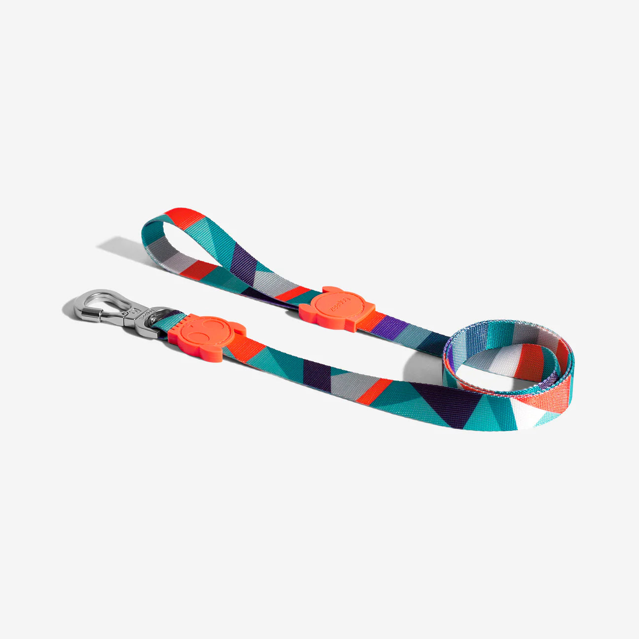 A colourful pet leash features a geometric pattern in turquoise, orange, and purple, with a metal clip and a textured grip.
