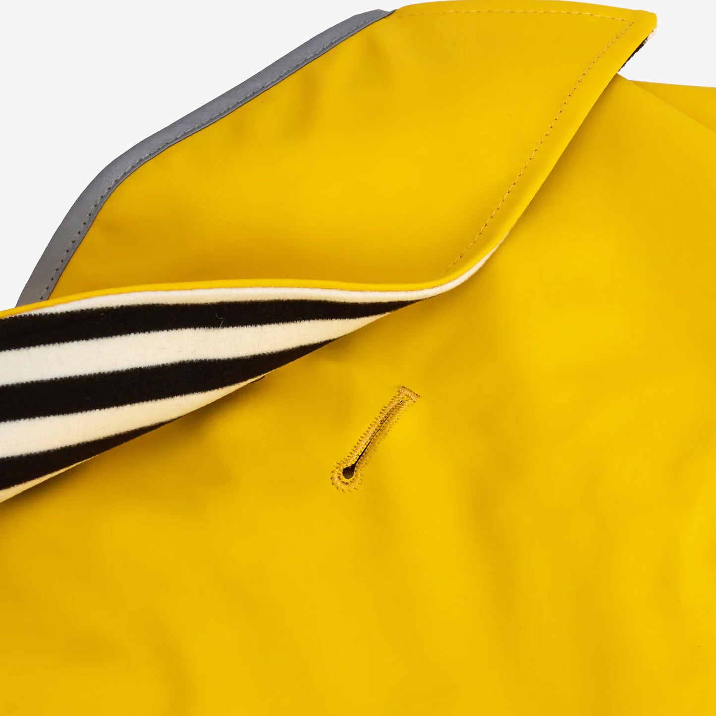 Close-up of a yellow jacket's collar, featuring grey reflective lining and a striped blue and white inner layer, with a small slot visible on the fabric.