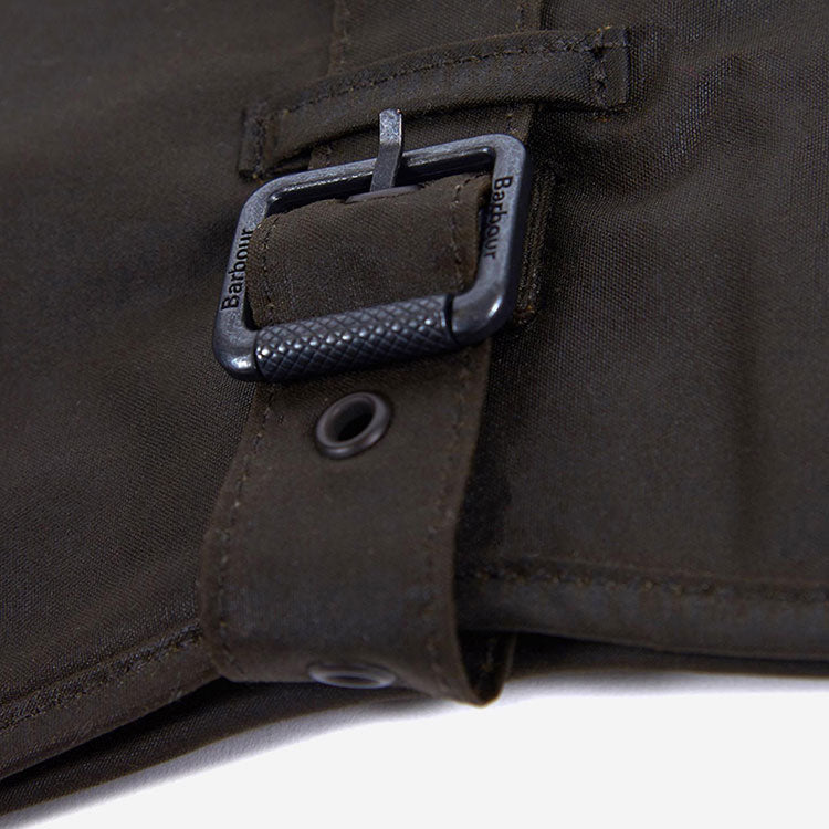 Close-up of a dark green dog jacket strap with a textured black metal buckle, featuring the Barbour logo.