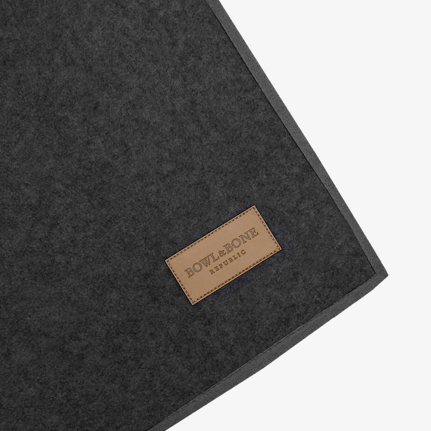 A dark wool blanket with a "BOWL&BONE REPUBLIC" leather logo patch. Sitting on a white background.