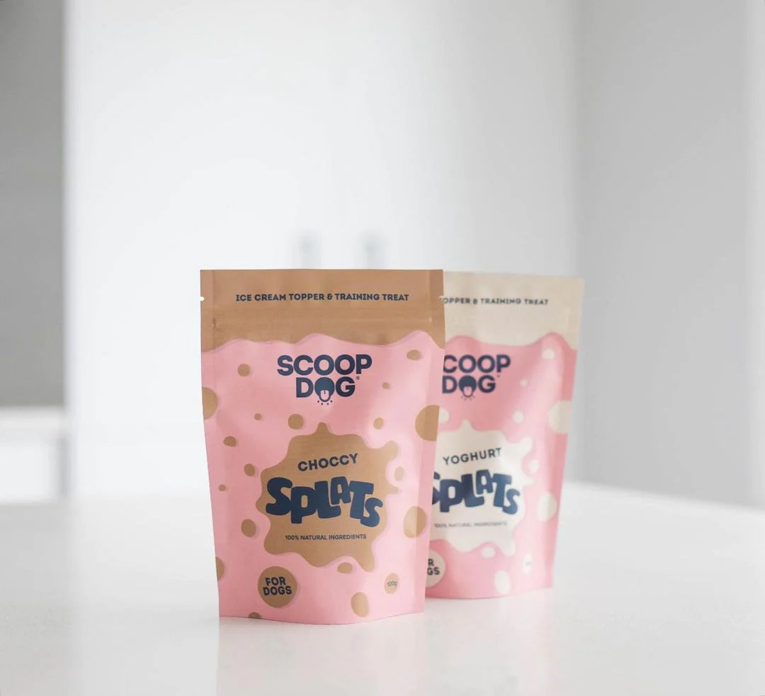 Two packs of Scoop Dog ice cream toppers for dogs, labeled "Choccy Splat" and "Yoghurt Plops," on a white surface.