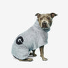 A dog wearing a cozy grey bathrobe with a towel texture, with 'dog' text on the back. Sitting against a white background.