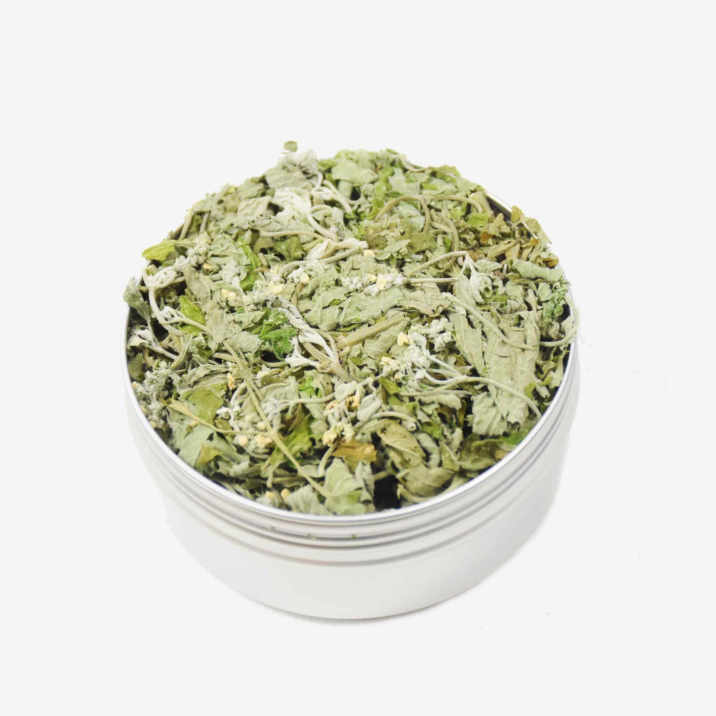 Dried herbs in a small open metal tin, isolated on a white background.