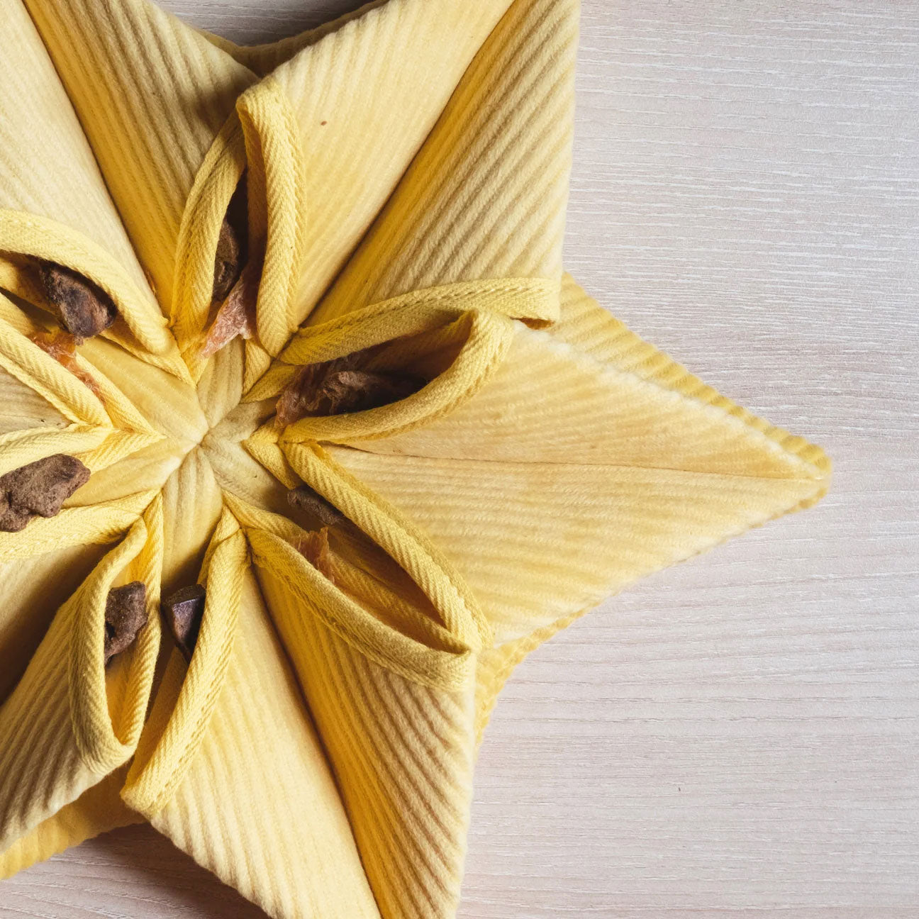 Close up of Lambwolf Collective's small snuffle flower shaped matt, Hoshi in yellow, stuffed with dog treats.