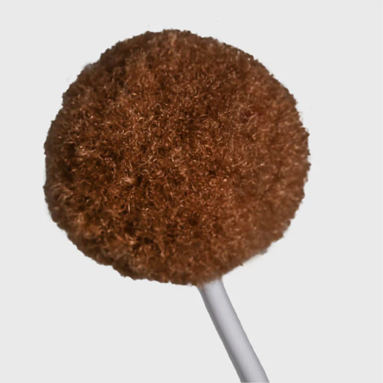 A brown, fuzzy circular pom pom on a white stick against a white background.