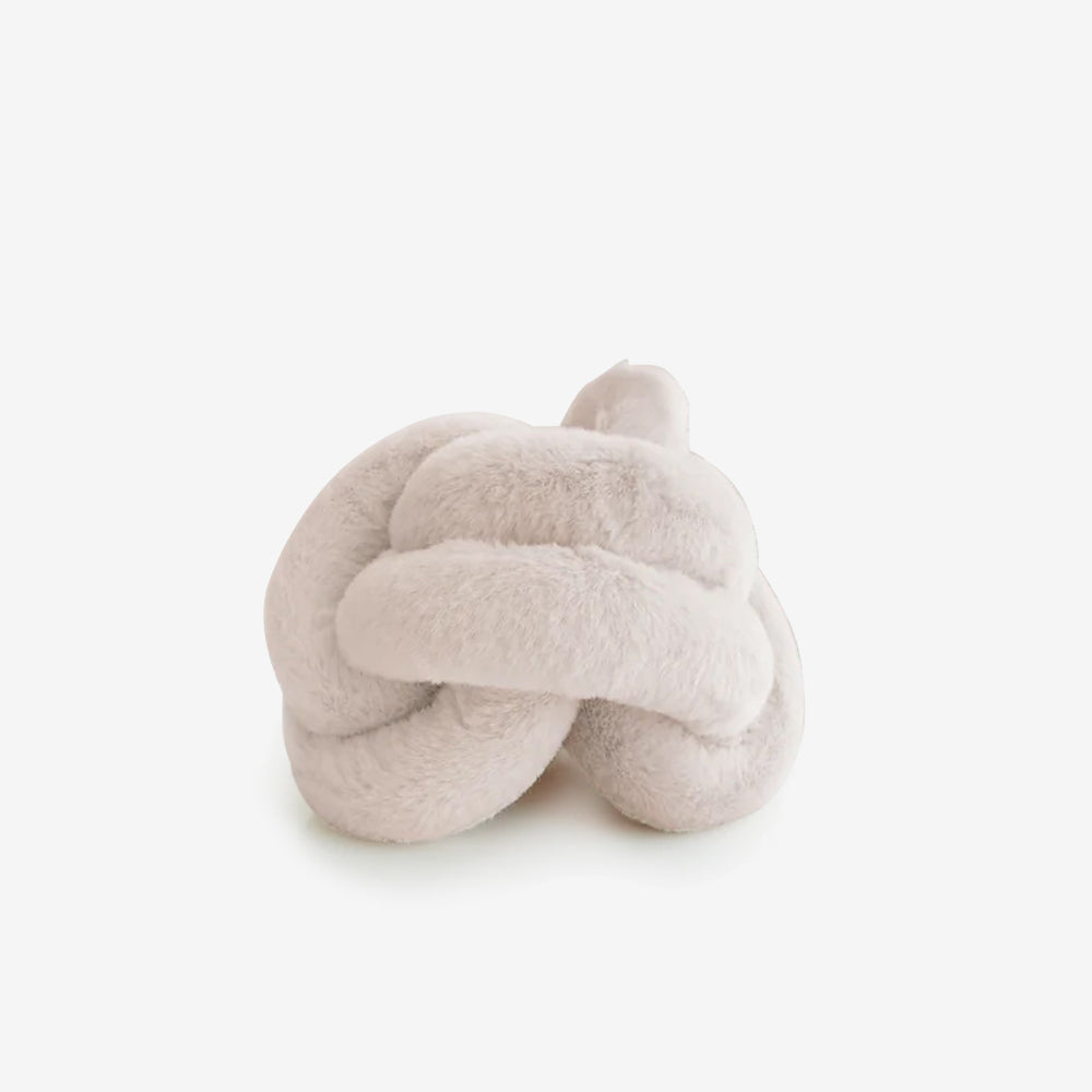 A soft, plush cream-coloured knot-shaped pillow resting on a white background, exuding a cozy and inviting aesthetic.