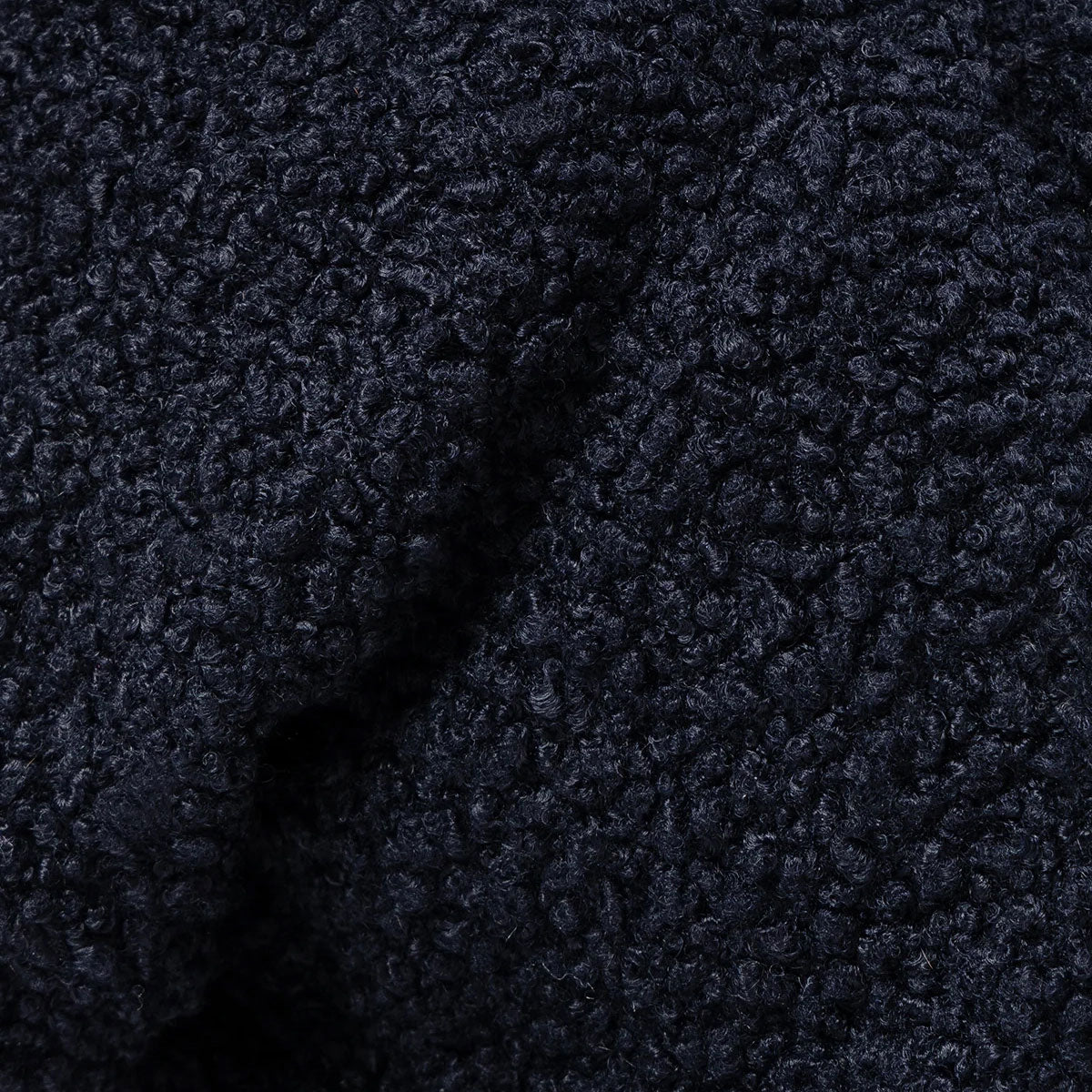 close up bobbly texture of a dark navy blue dog jumper.