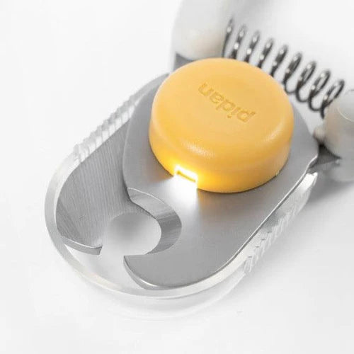 A close-up of a silver manual pet nail clippers with a yellow light.