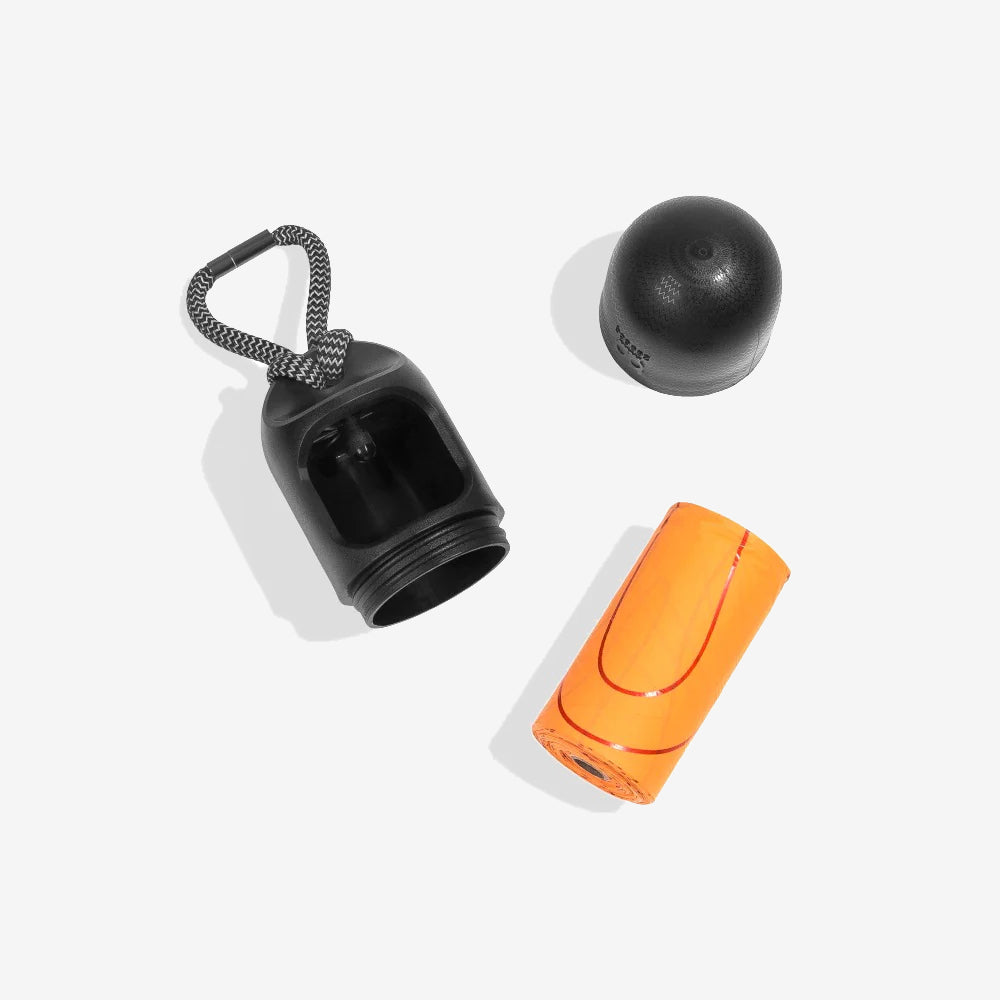 Orange poo bags sit alongside a black textured capsule shaped poo bag case, with a black and white elasticated adjustable strap
