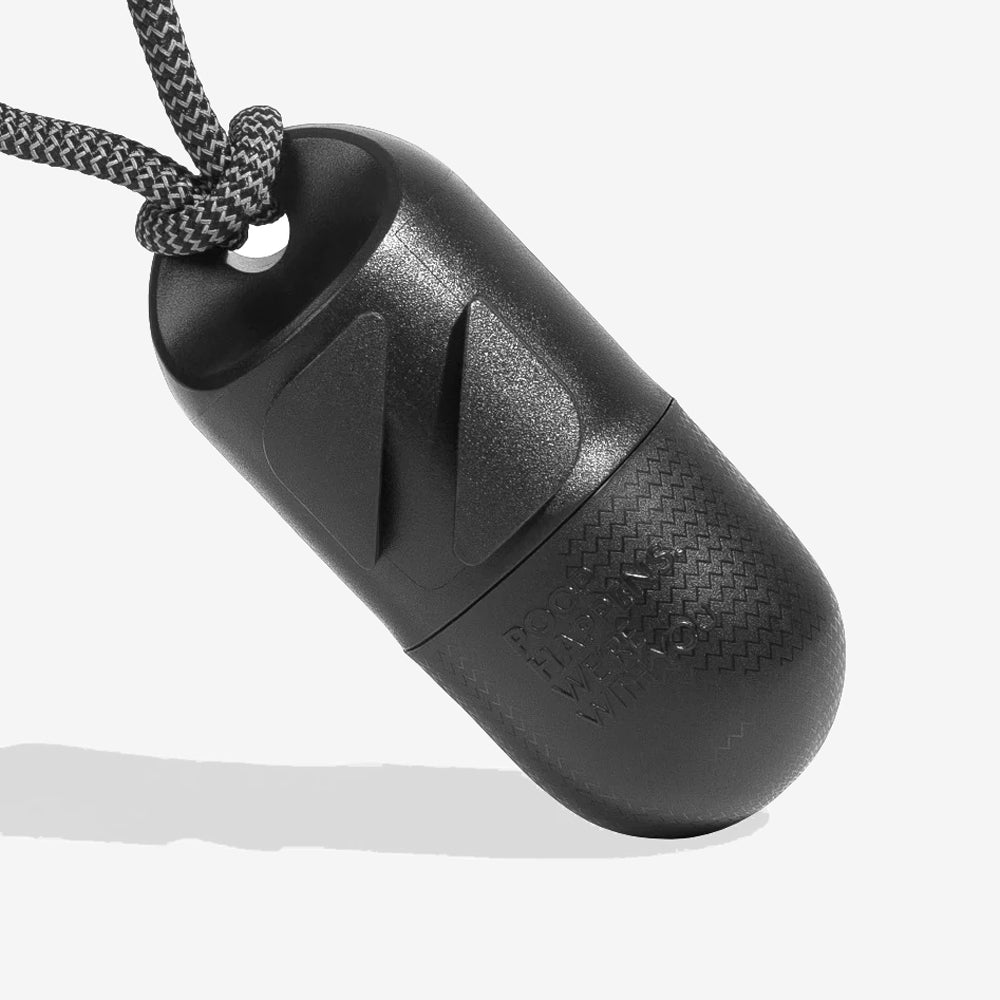 Close-up of a black poo bag case, textured capsule-shaped container with a hanging strap, designed for waterproof storage.