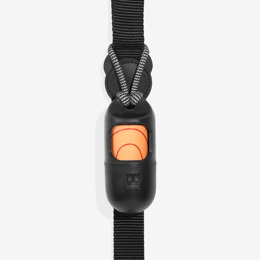 A close-up of a black dog leash clasp with an orange pouch visible, featuring a woven strap and a braided cord attachment.