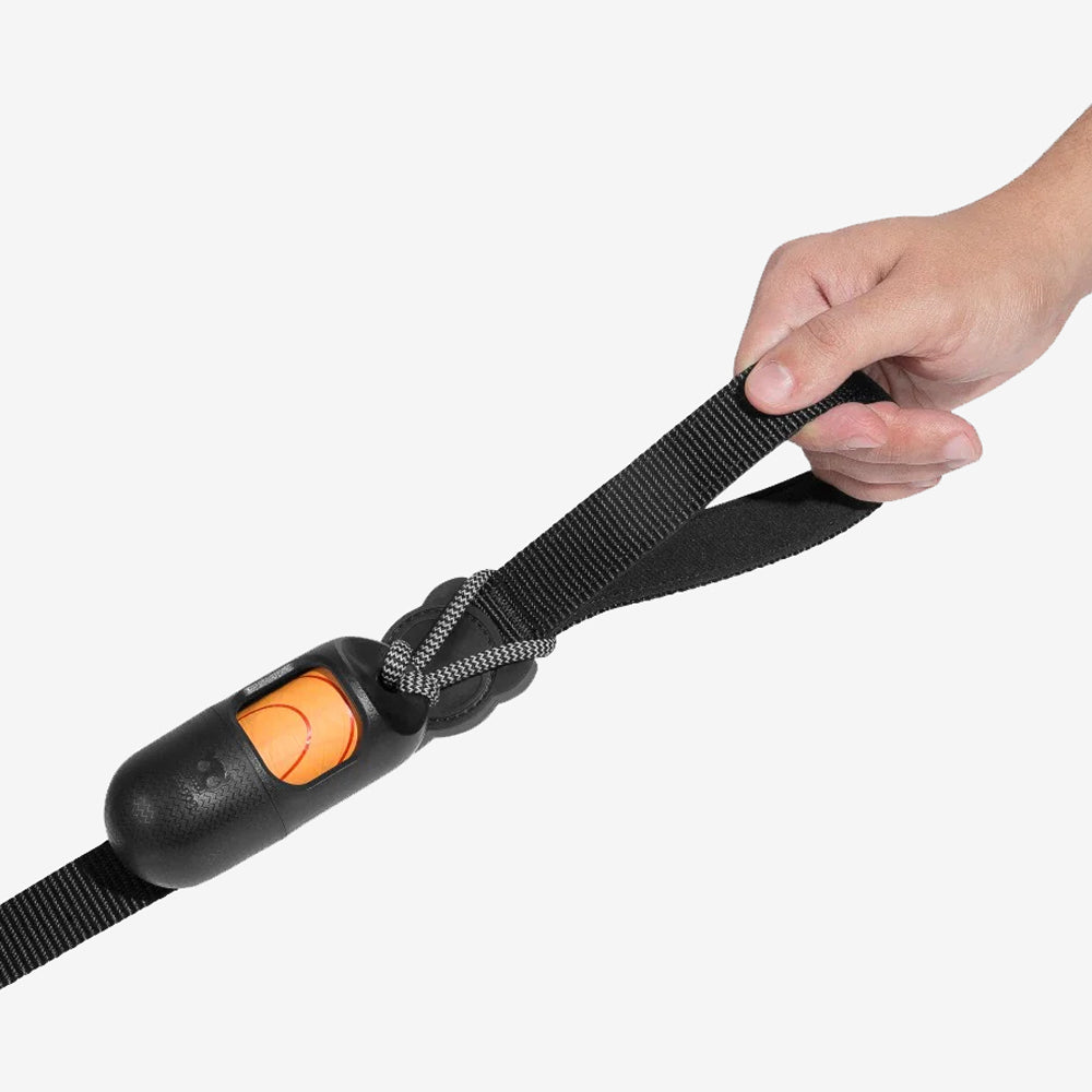 A hand gripping a black strap attached to a black and orange device, designed for adjusting length or securing items.